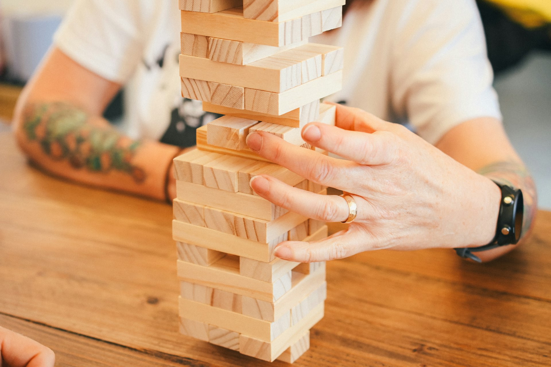 a person playing with a wooden tower on a table